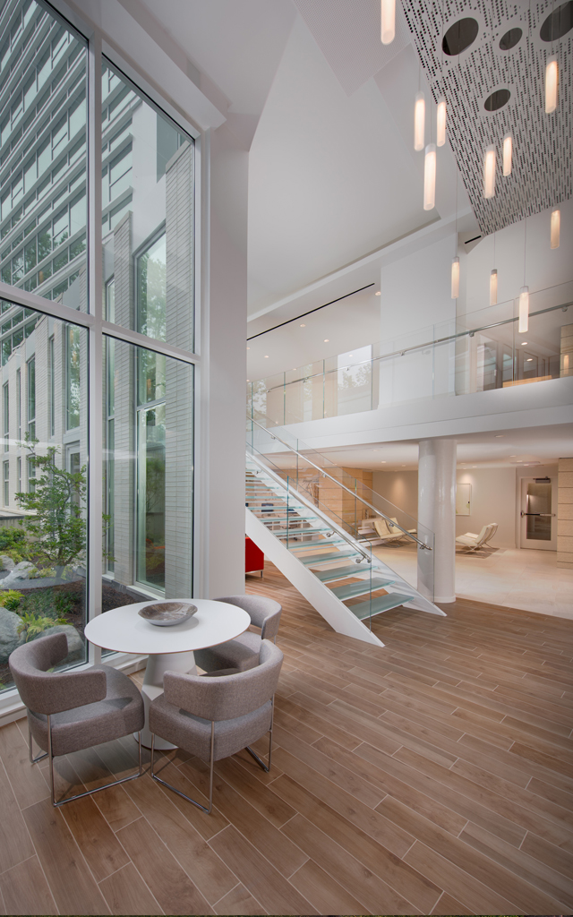 Brightly lit welcome area with modernist tables, chairs, and staircase