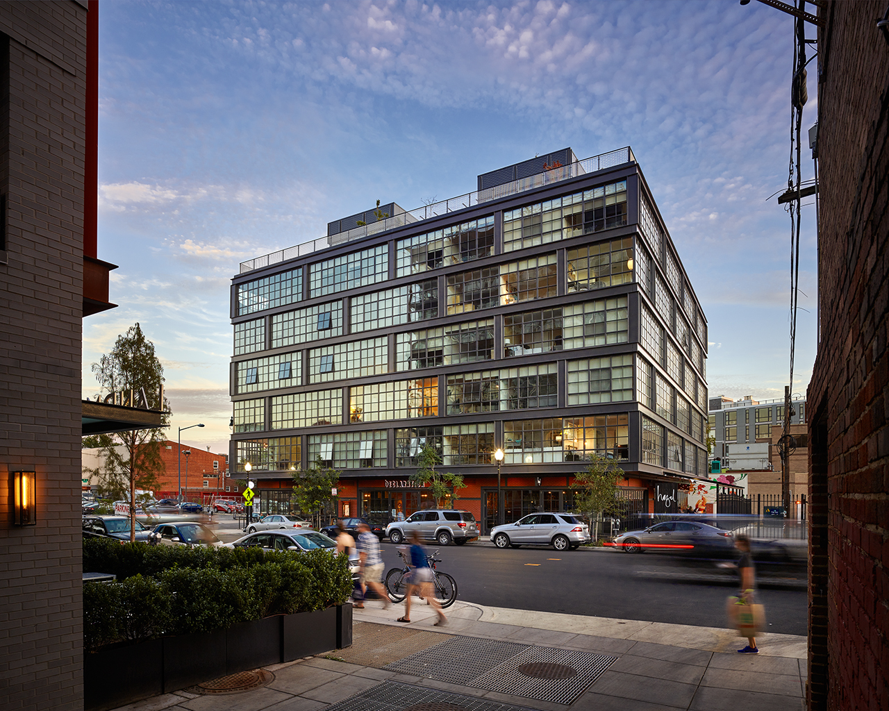 Large building with many windows at sunset and crowds walking past