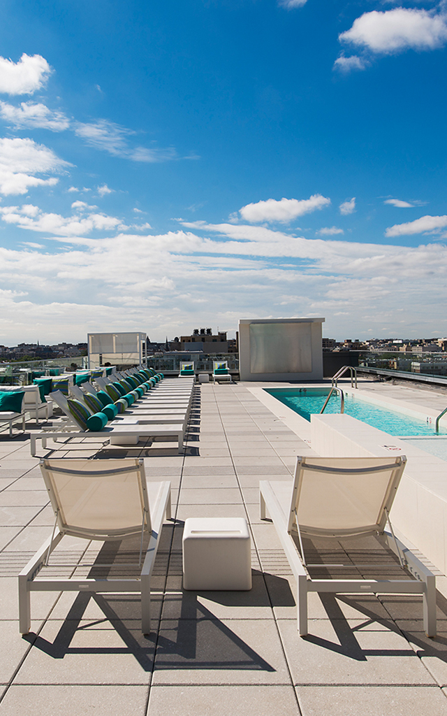 Brightly lit rooftop with pool and deck chairs
